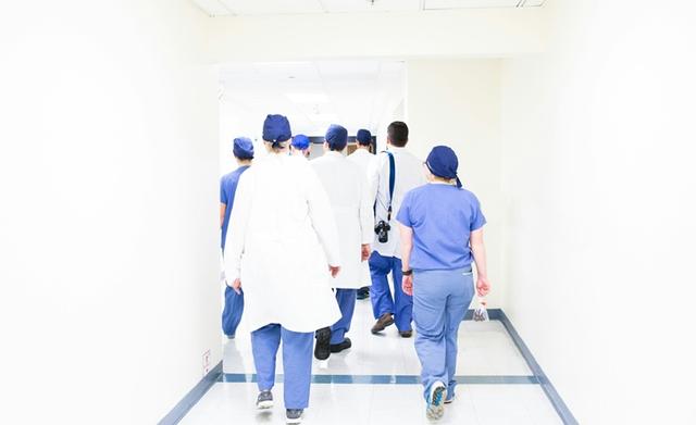 Des médecins en blouse bleu marchent de dos