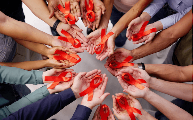 Des mains tiennent des rubans rouges