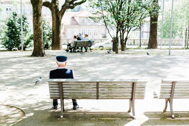 un vieux monsieur est assis sur un banc sur la place du village