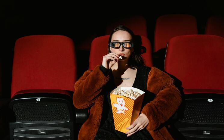 femme seule au cinéma qui mange du popcorn