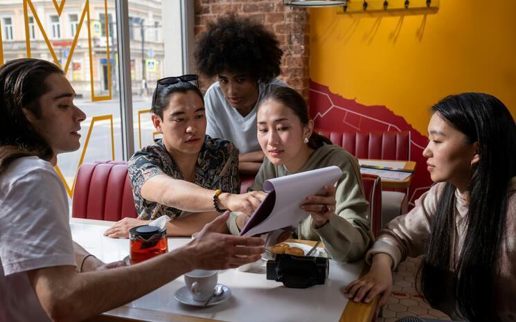 Groupe de 5 personnes qui discutent dans un café